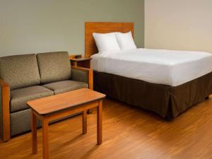 Extended Stay America Select Suites - Provo - American Fork في ليهي: غرفة نوم بسرير واريكة بجانب كرسي