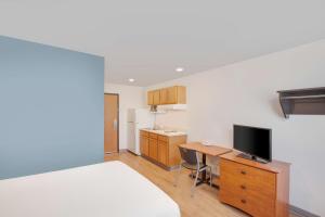 a room with a desk with a television and a kitchen at Extended Stay America Select Suites - Springdale in Springdale