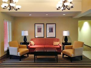 uma sala de estar com um sofá vermelho e duas cadeiras em Extended Stay America Suites - Charleston - Airport em Charleston