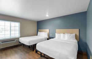 2 camas en una habitación con paredes azules y ventana en Extended Stay America Select Suites - Firestone, en Firestone