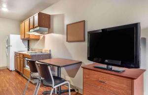 a kitchen with a small table and a television on a cabinet at Extended Stay America Select Suites - Shreveport - Airport in Shreveport