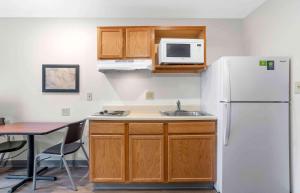 a kitchen with a white refrigerator and a table at Extended Stay America Select Suites - Springfield - South - Battlefield in Springfield
