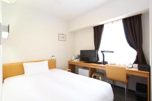 a bedroom with a bed and a desk with a computer at Hotel BB Fast Sakuranbo Higashine in Higashine