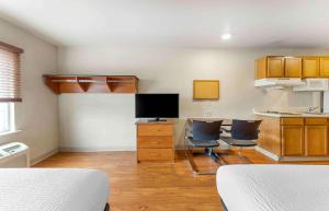 Zimmer mit 2 Stühlen und einem Schreibtisch mit einem TV in der Unterkunft Extended Stay America Select Suites - Oklahoma City - Norman in Norman