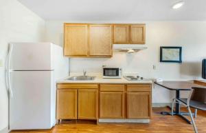 a kitchen with wooden cabinets and a white refrigerator at Extended Stay America Select Suites - Oklahoma City - Del City in Del City