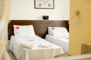 duas camas num quarto com lençóis brancos e toalhas em City Bauru Reserve Agora em Bauru