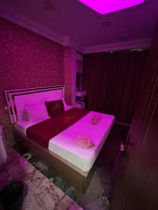 New Abdeen palace hostel في القاهرة: غرفة نوم بسرير كبير مع اضاءة ارجوانية
