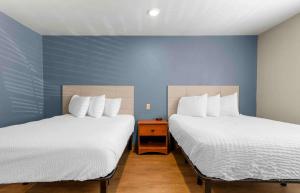 Duas camas num quarto com paredes azuis em Extended Stay America Select Suites - Fayetteville - I-49 em Fayetteville