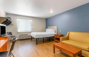 um pequeno quarto com uma cama e um sofá em Extended Stay America Select Suites - Fayetteville - I-49 em Fayetteville