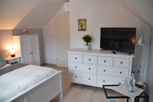 a bedroom with a white dresser with a flat screen tv at Superior - Ferienhaus am Engelsbach mit Pool im Thüringer Wald in Engelsbach