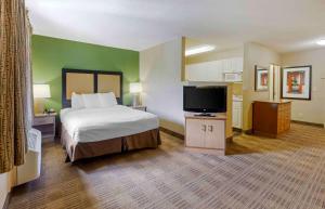 a hotel room with a bed and a flat screen tv at Extended Stay America Select Suites - Raleigh - RTP - 4610 Miami Blvd in Durham