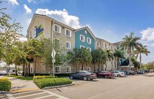 un edificio con coches estacionados en un estacionamiento en Extended Stay America Select Suites - Fort Lauderdale - Airport - West en Davie