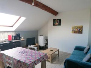 sala de estar con mesa y sofá azul en Appartement climatisé avec parking privé gratuit en Doué-la-Fontaine