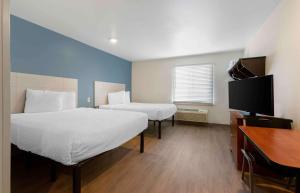 Cette chambre comprend deux lits, un bureau et une télévision. dans l'établissement Extended Stay America Select Suites - El Paso - East, à El Paso