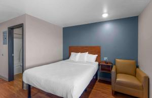 a bedroom with a large bed and a chair at Extended Stay America Suites - Denver - Airport in Aurora