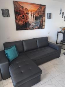 eine schwarze Couch in einem Wohnzimmer mit einem Gemälde an der Wand in der Unterkunft Vista taurito Ely in Taurito