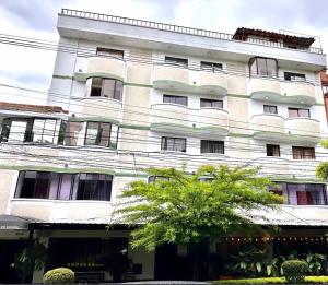 ein großes weißes Gebäude mit einem Baum davor in der Unterkunft Hotel Balcones del Estadio in Medellín