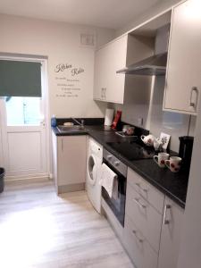 cocina con fregadero y fogones horno superior en Máire Toiréasa – cosy refurbished property in the Gaeltacht Quarter, en Belfast