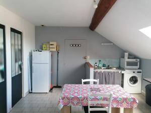 a kitchen with a table and a white refrigerator at Appartement climatisé avec parking privé gratuit in Doué-la-Fontaine