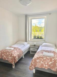 two beds in a room with a window at Apartamenty Golf Dyndeby in Neksø