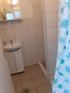 a bathroom with a sink and a shower curtain at Pihenés a Malomtónál privát bérlemény in Tapolca
