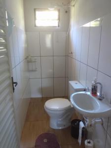 a white bathroom with a toilet and a sink at Rancho Belo in São José da Barra