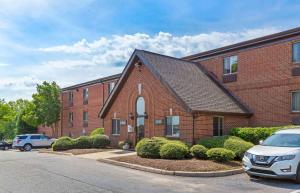 a brick building with a car parked in front of it at Extended Stay America Select Suites - Greensboro - Wendover Ave in Greensboro
