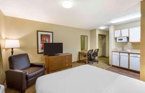 a hotel room with a bed chair and a kitchen at Extended Stay America Select Suites - Greensboro - Wendover Ave in Greensboro