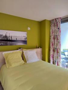 a bedroom with a bed with green walls and a window at Les Valcaprimontoises in Chaudfontaine