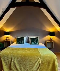 Cette chambre comprend un grand lit avec des draps jaunes et deux lampes. dans l'établissement Flor du Mont Gîte, à Pontorson