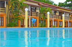 un hôtel avec une piscine en face d'un bâtiment dans l'établissement Res Village do Bosque 03, à Porto Seguro
