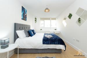 um quarto branco com uma cama grande e almofadas azuis em Zeus Apartment - The Thunder of Town em Southampton