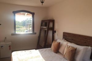 Schlafzimmer mit einem Bett und einem Fenster in der Unterkunft Chalé Serra do Ouro in Diamantina