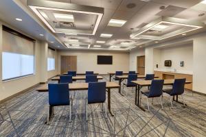 una sala de conferencias con mesas, sillas y una pantalla en Holiday Inn Express Holly Springs - Raleigh Area, an IHG Hotel en Holly Springs