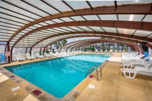 a pool with white chairs and a large swimming pool at Mobil-home Excellence - 3 Chambres in Chaumont-sur-Loire