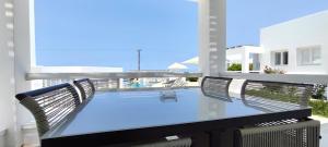 a glass table on a balcony with a view of the ocean at Lemon Tree Houses in Áno Meriá