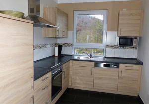 eine Küche mit Holzschränken, einem Waschbecken und einem Fenster in der Unterkunft Ferienhaus Fischbachtal in Heimbach