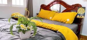 a bed with yellow pillows and a vase with flowers at Lavender House in Ấp Kim Thạch