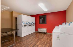 Habitación con electrodomésticos blancos y pared roja. en Extended Stay America Suites - Columbus - Worthington, en Worthington