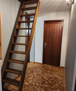 Una escalera de madera en una habitación con puerta. en LA VILLA MONTA, en Vendays-Montalivet