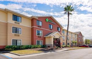 a hotel with a palm tree in front of a building at Extended Stay America Suites - Melbourne - Airport in Melbourne