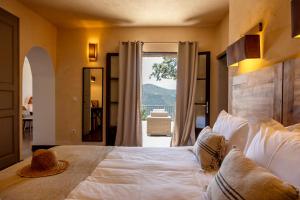 a bedroom with a large white bed with a large window at Hôtel Case Latine in Lama
