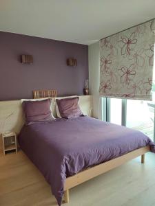 een slaapkamer met een bed met paarse lakens en een raam bij Les Valcaprimontoises in Chaudfontaine