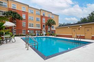 uma piscina com mesas e cadeiras e um edifício em Extended Stay America Suites - Orlando - Convention Center - 6443 Westwood em Orlando