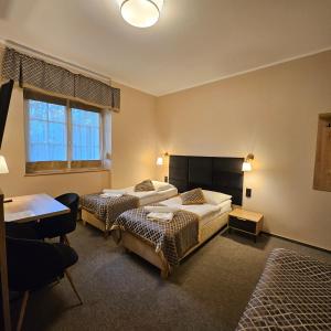 a bedroom with two beds and a table and a desk at Willa Kłodzko - Zacisze in Kłodzko