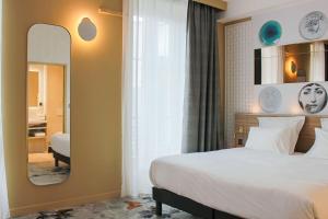 - une chambre d'hôtel avec un lit et un miroir dans l'établissement Brit Hotel Limoges Centre Gare - Hôtel & Spa, à Limoges