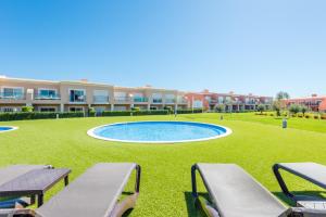une piscine au milieu d'une pelouse avec des bancs dans l'établissement Casa Estrella at Boavista Resort, à Lagos