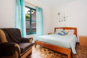 um quarto com uma cama, uma cadeira e uma janela em Slice of Paradise- Palheiro de Golf no Funchal