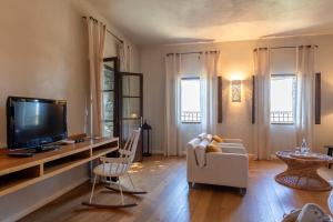 a living room with a tv and a couch and chairs at Hôtel Case Latine in Lama