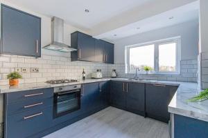 een keuken met blauwe kasten en een wastafel bij New Stylish 5BD, 5min from town in Cardiff